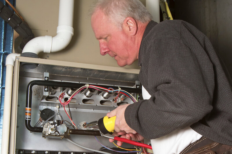 HVAC Technician looking at the insides of a Furnace