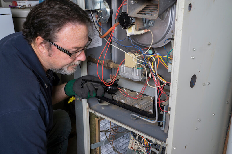 Technician looking at the inside of a furnace